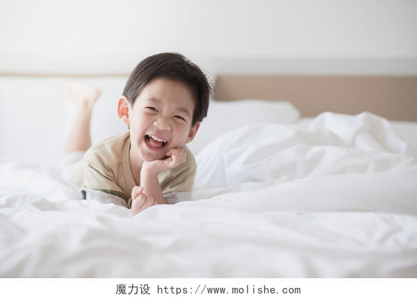 开心的小孩可爱亚洲孩子趴在白色的床上